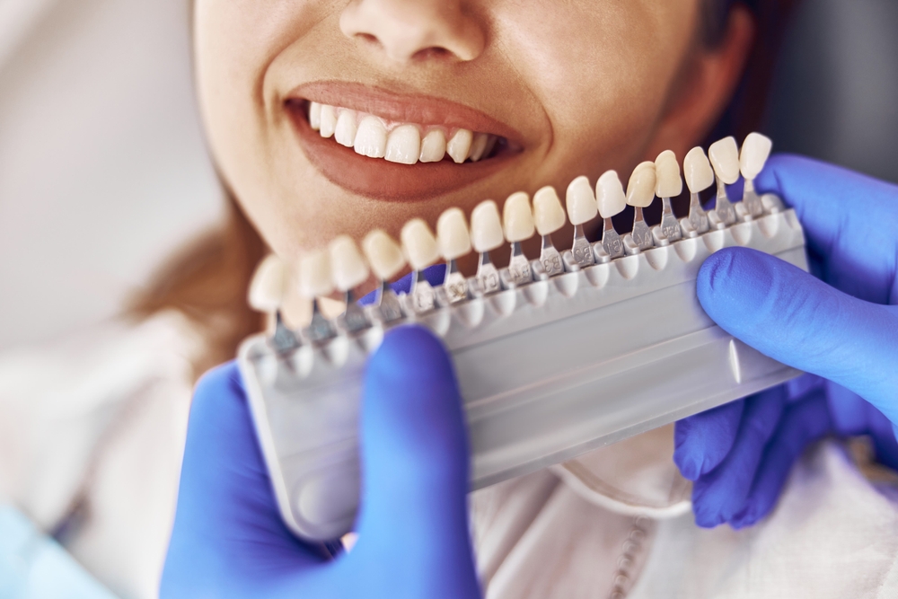 Professional doctor is choosing a color of teeth in modern dental clinic